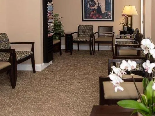 The waiting room at Rehoboth Beach Dental, with chairs, a lamp and white orchids.